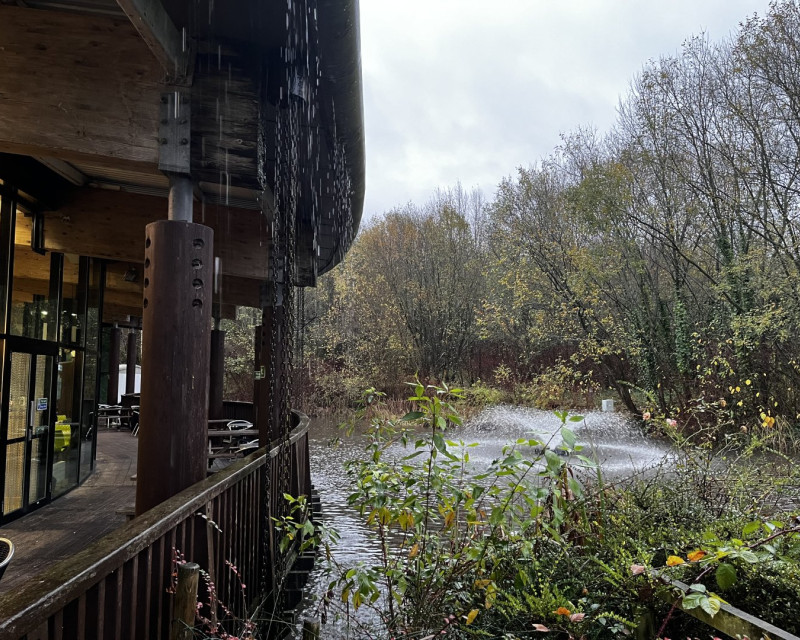 Pond and fountain outside Stafford Services southbound, rain pouring off the roof.