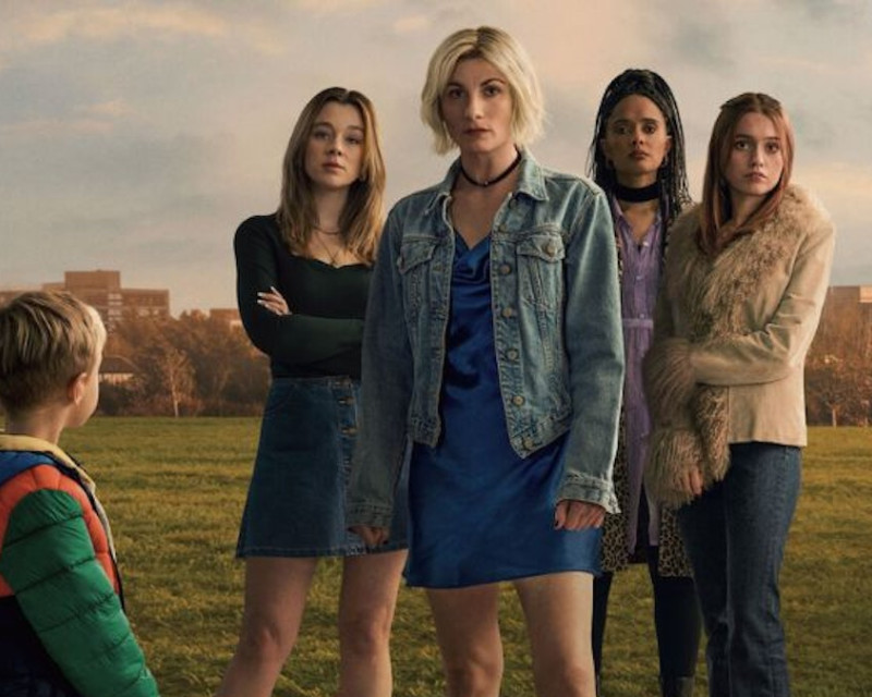 Cover image from Toxic Town, with four women in a field in the centre of the picture, looking towards the camera as a young boy in a green coat looks back towards them.