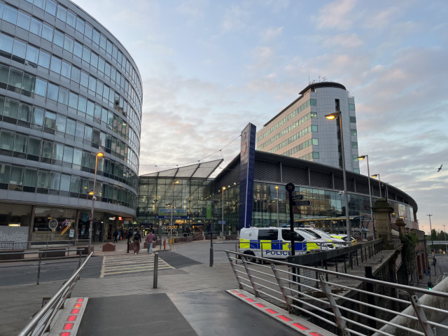 Entrance to Manchester Piccadilly train station on a clear bright morning, with light scattered clouds