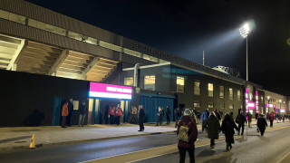 Floodlit view of the Bob Lord Stand from outside on Harry Potts Way as passers by head into the stadium for kick-off.
